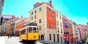 Colorful buildings, historic tram, and sunny Lisbon street.